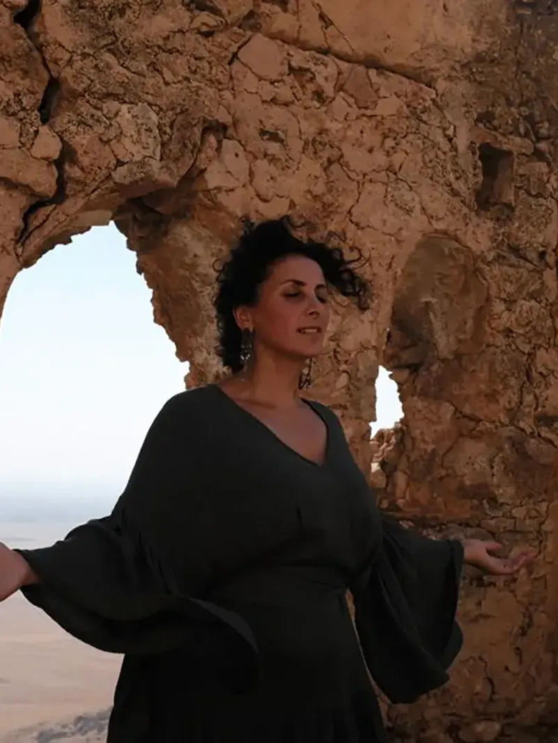 Maria Kaplan in grünem Kleid, singend im Naturlicht